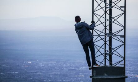 man climbing on tower near buildings at daytime